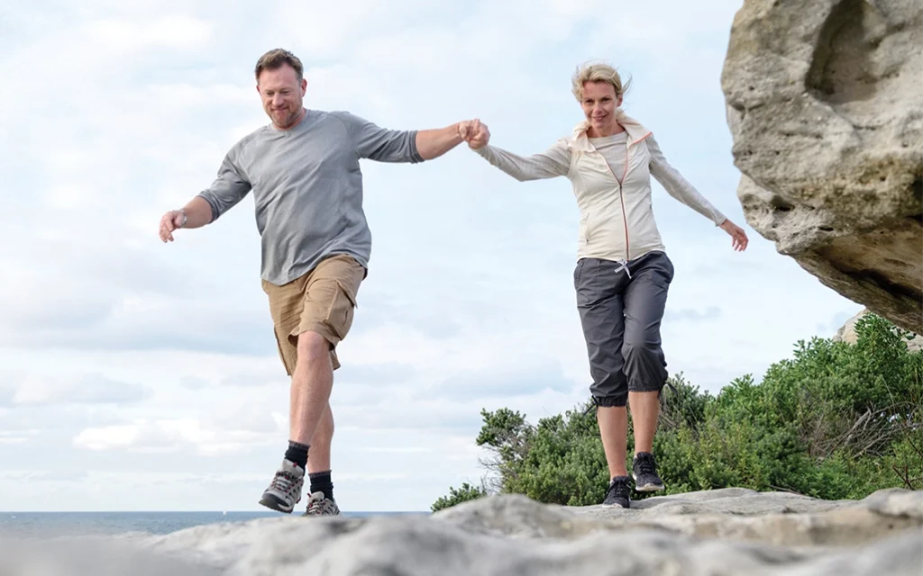 couple holding hands walking on beach